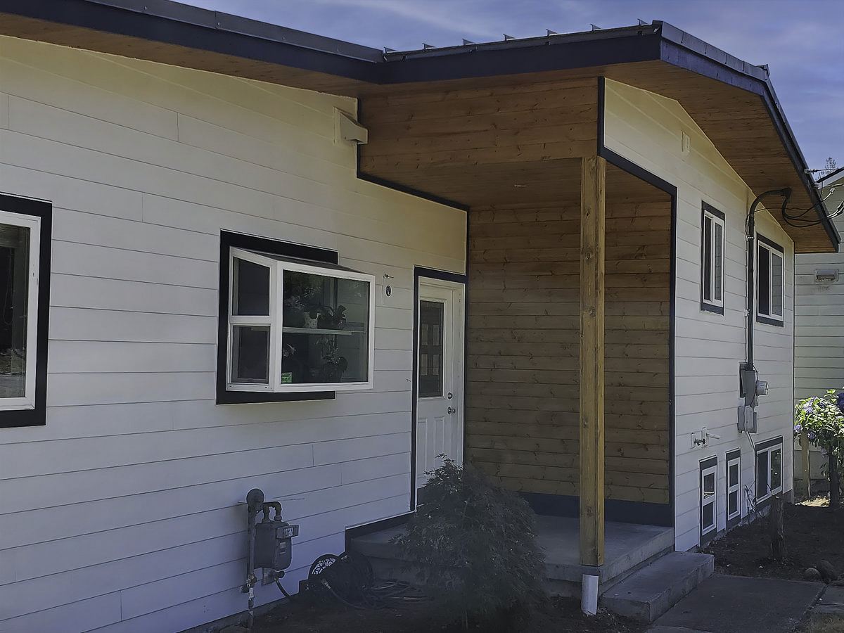 Covered entry siding with black trim and warm wood accent